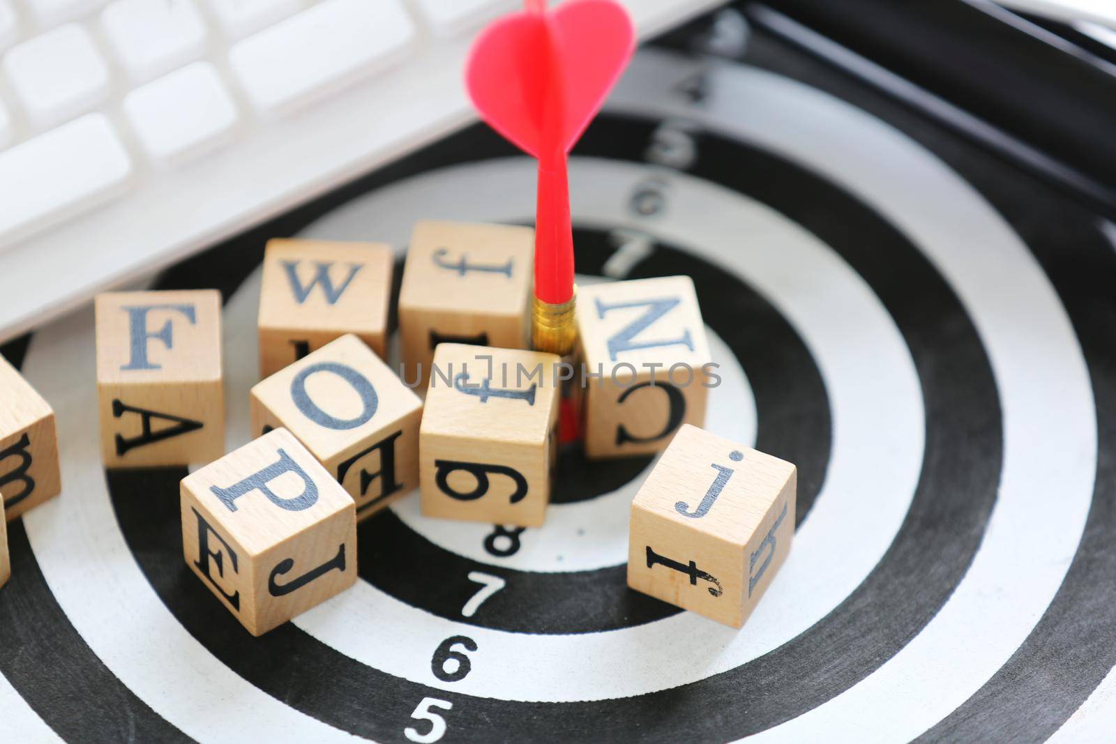 wooden cube with alphabet on target board and white keyboard 