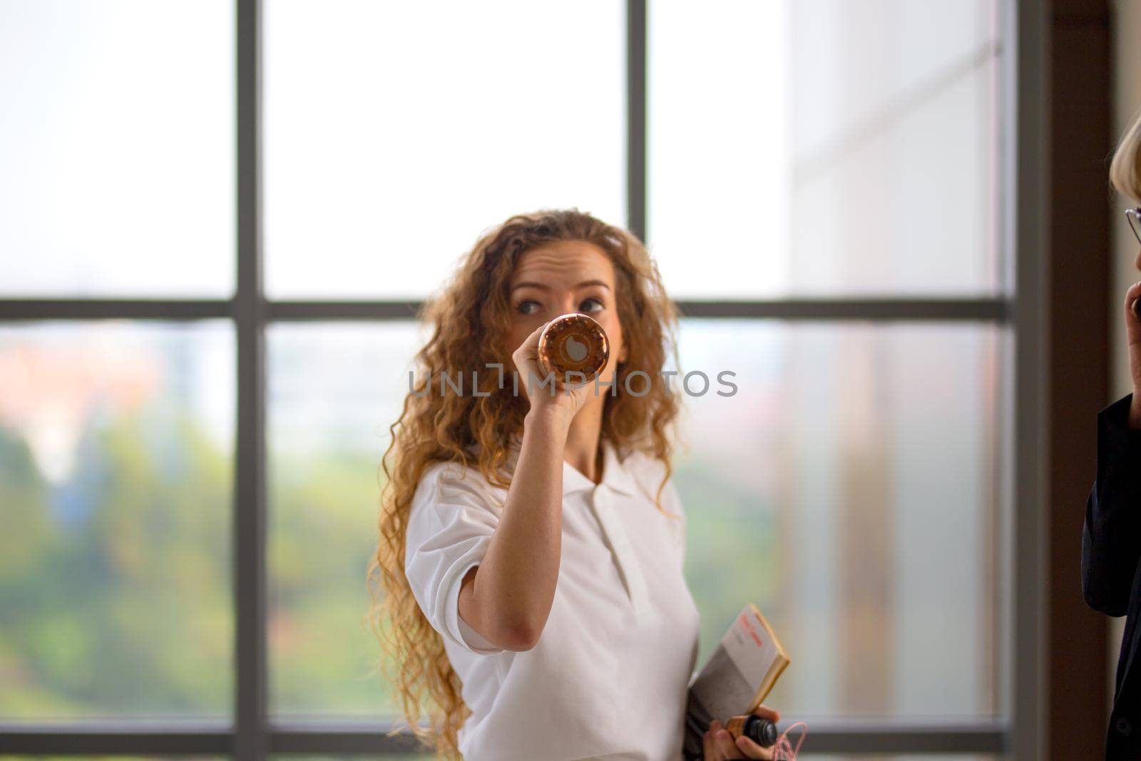 women white shirt with blonde hair drinking water in bottle