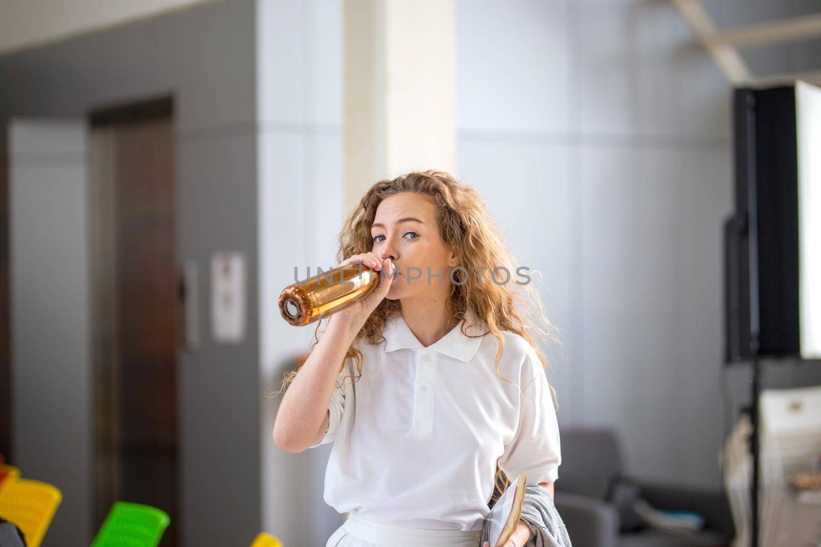 women white shirt with blonde hair drinking water in bottle by chuanchai