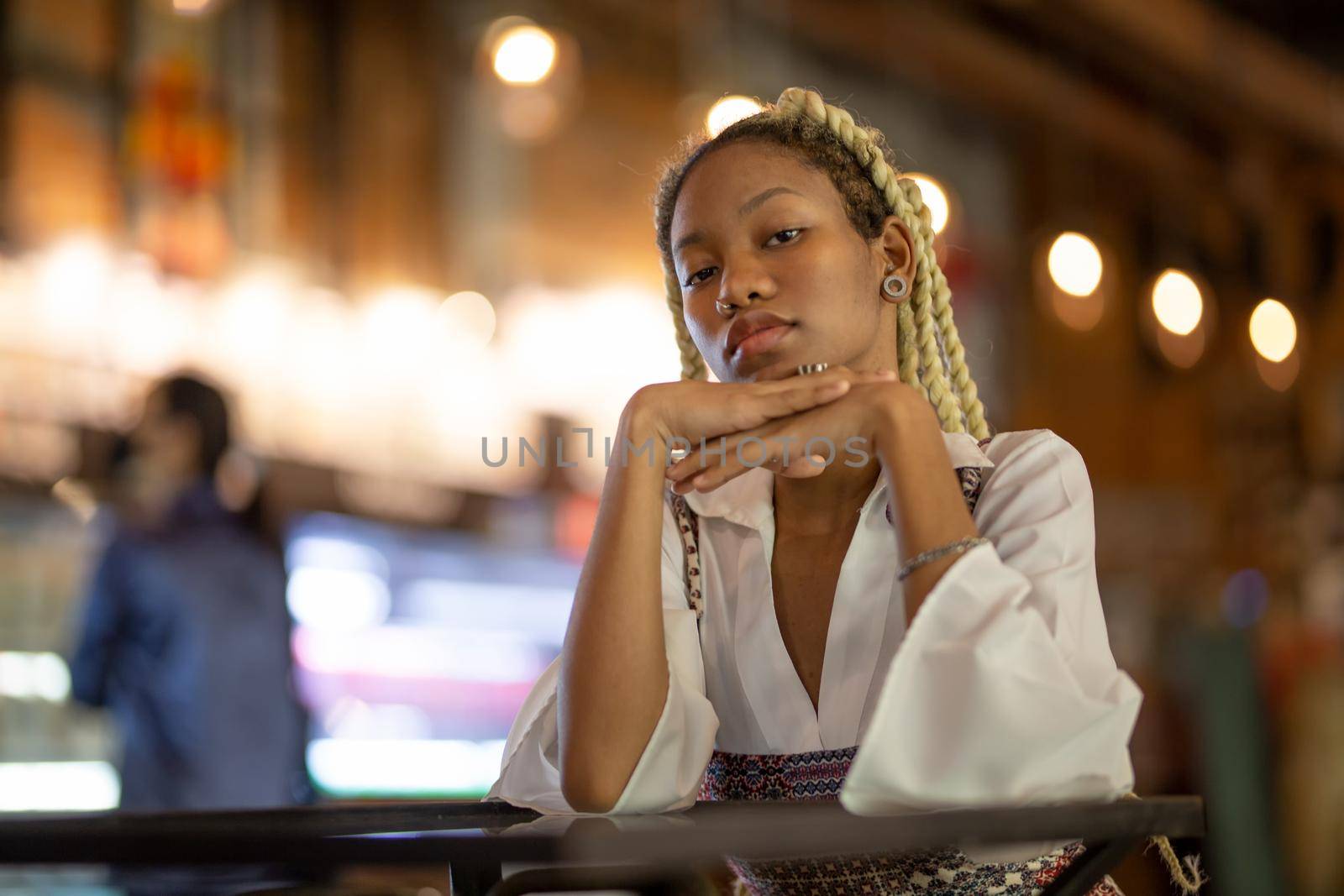 portrait of young african woman showing long braided hair next to face at urban street.