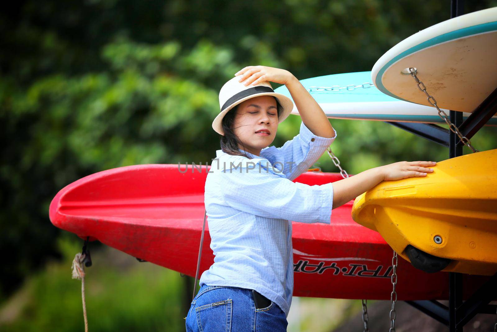 portrait of young Asian woman showing long braided standing by surfboard.