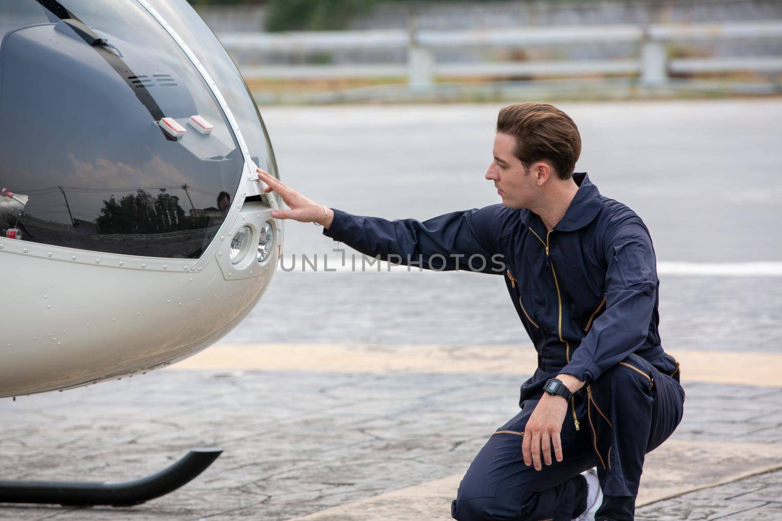 Commercial man pilot in technician suit standing in front of helicopter after check and maintenance engine	