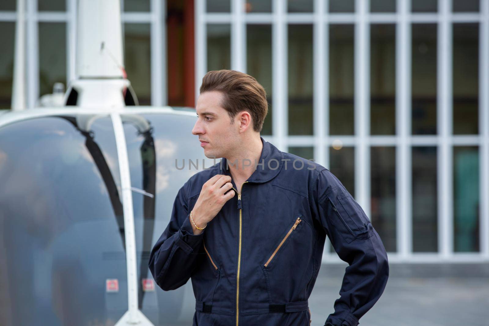 Commercial man pilot in technician suit standing in front of helicopter after check and maintenance engine	