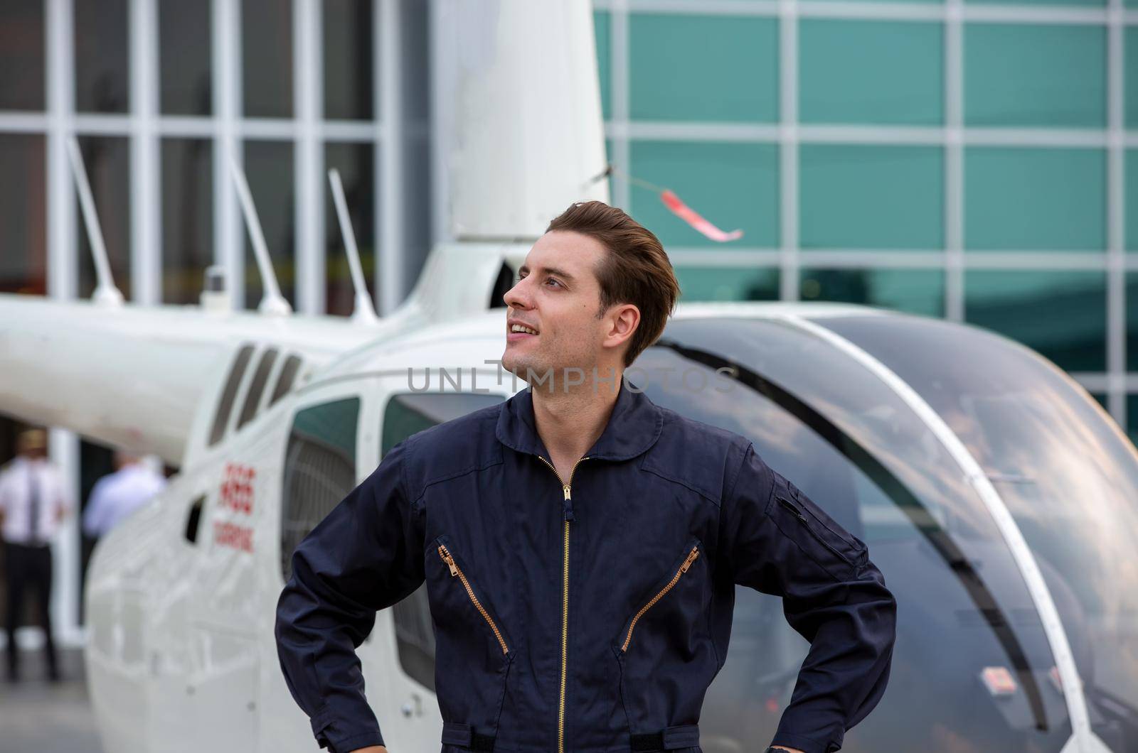 Commercial man pilot in technician suit standing in front of helicopter after check and maintenance engine	