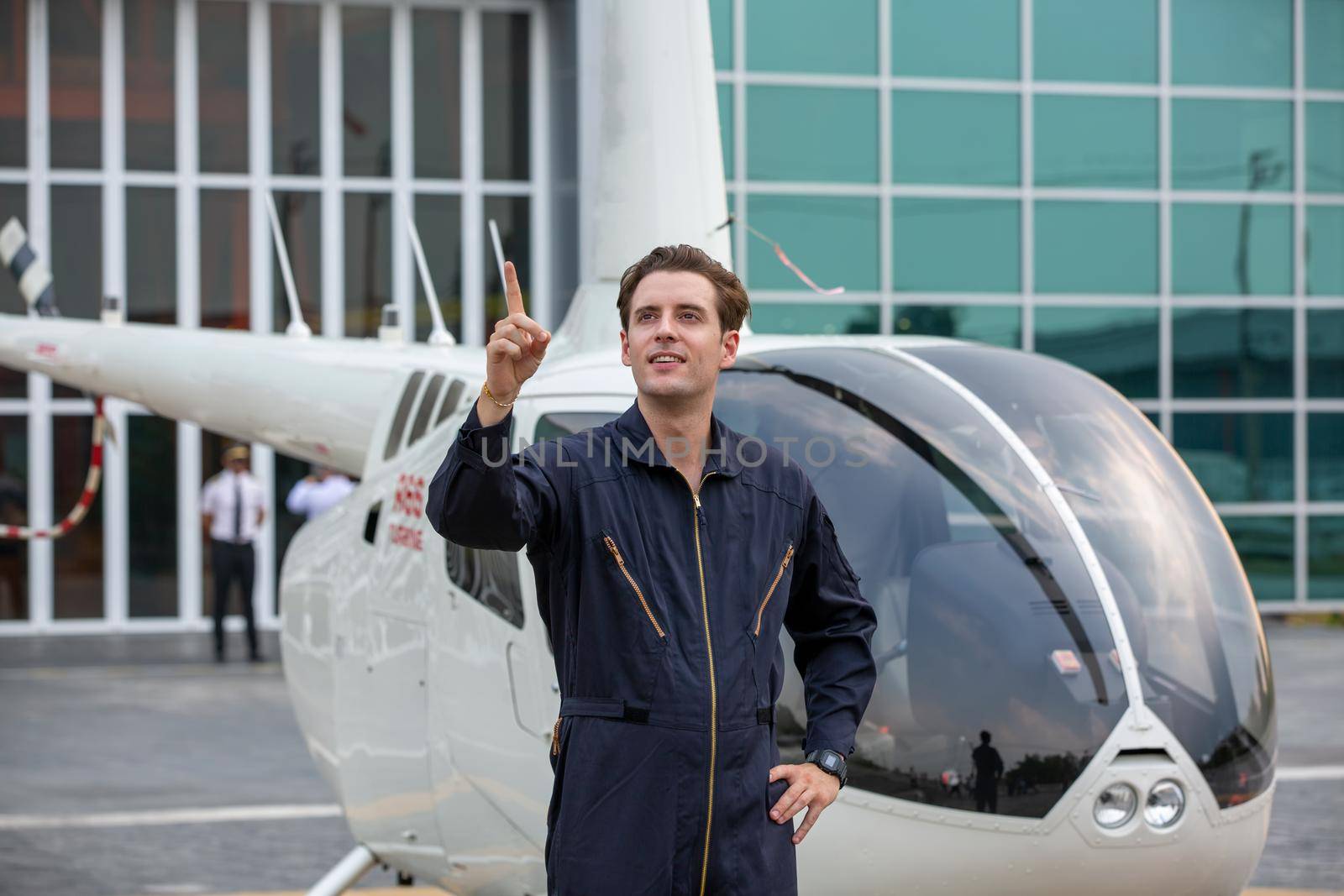 Commercial man pilot in technician suit standing in front of helicopter after check and maintenance engine	