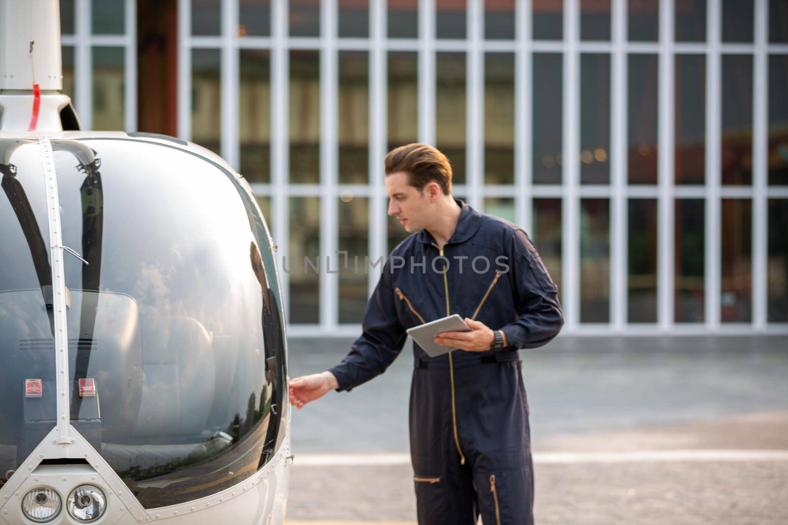 Commercial man pilot in technician suit standing in front of helicopter after check and maintenance engine	