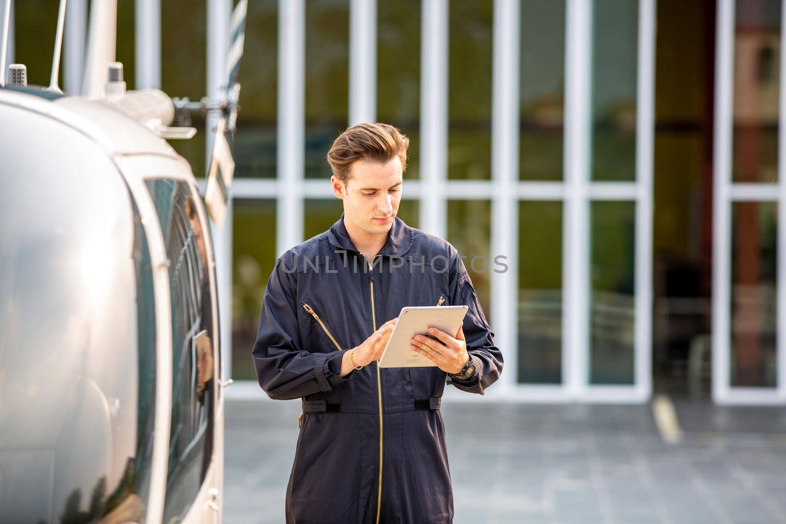 Commercial man pilot in technician suit standing in front of helicopter after check and maintenance engine	