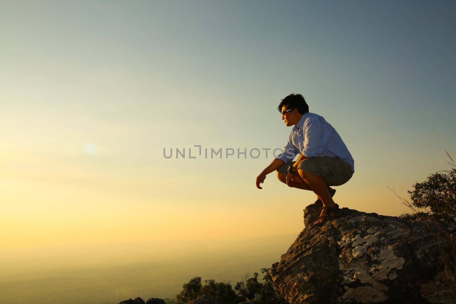 a man on a mountain top. Person on the rock. Sport and active life concept. Beauty world. by chuanchai