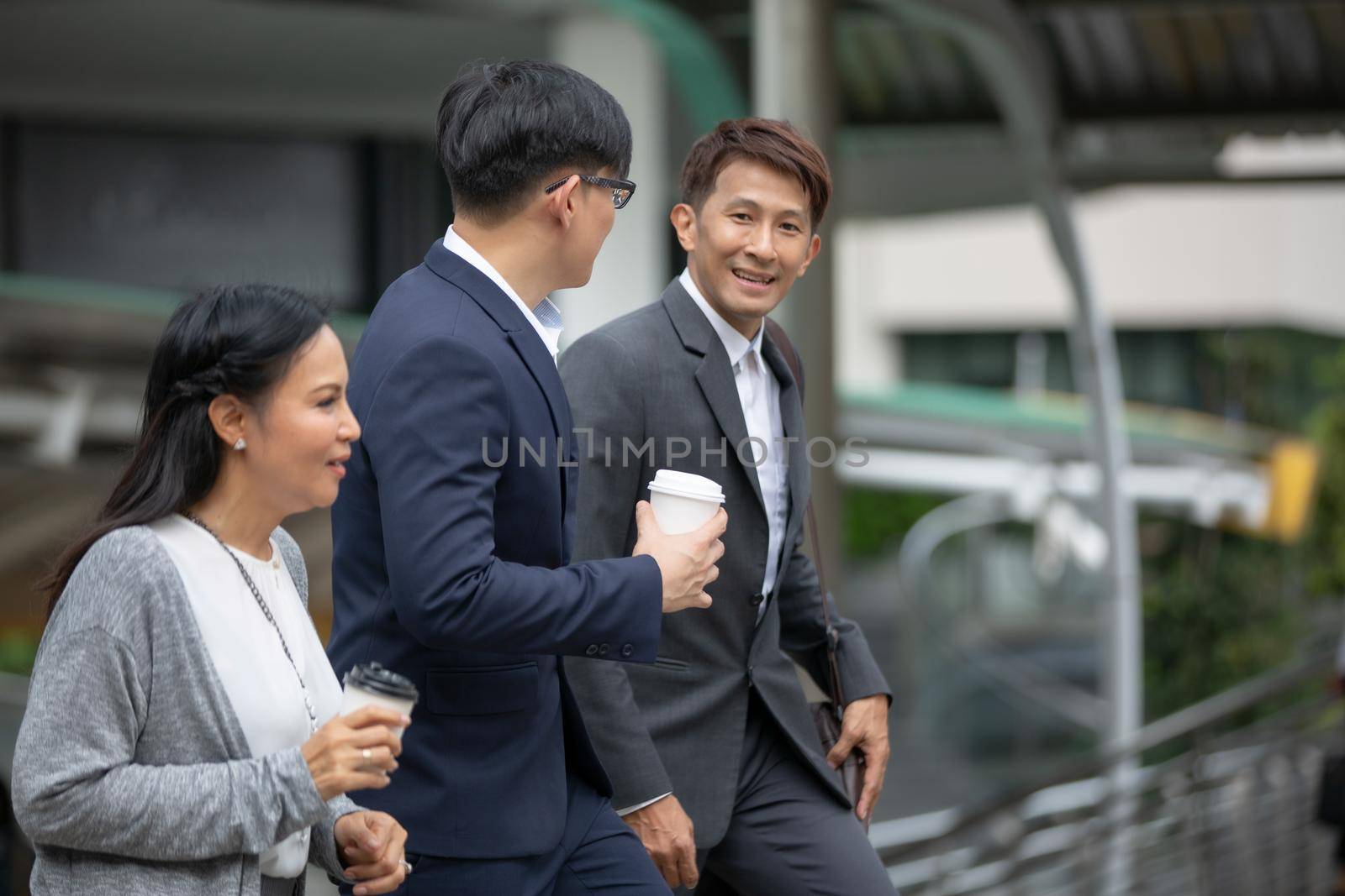 Businessman and businesswoman discussing work while walking outside office by chuanchai