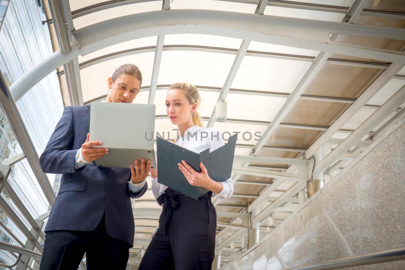 Businessman and businesswoman discussing work while walking outside office