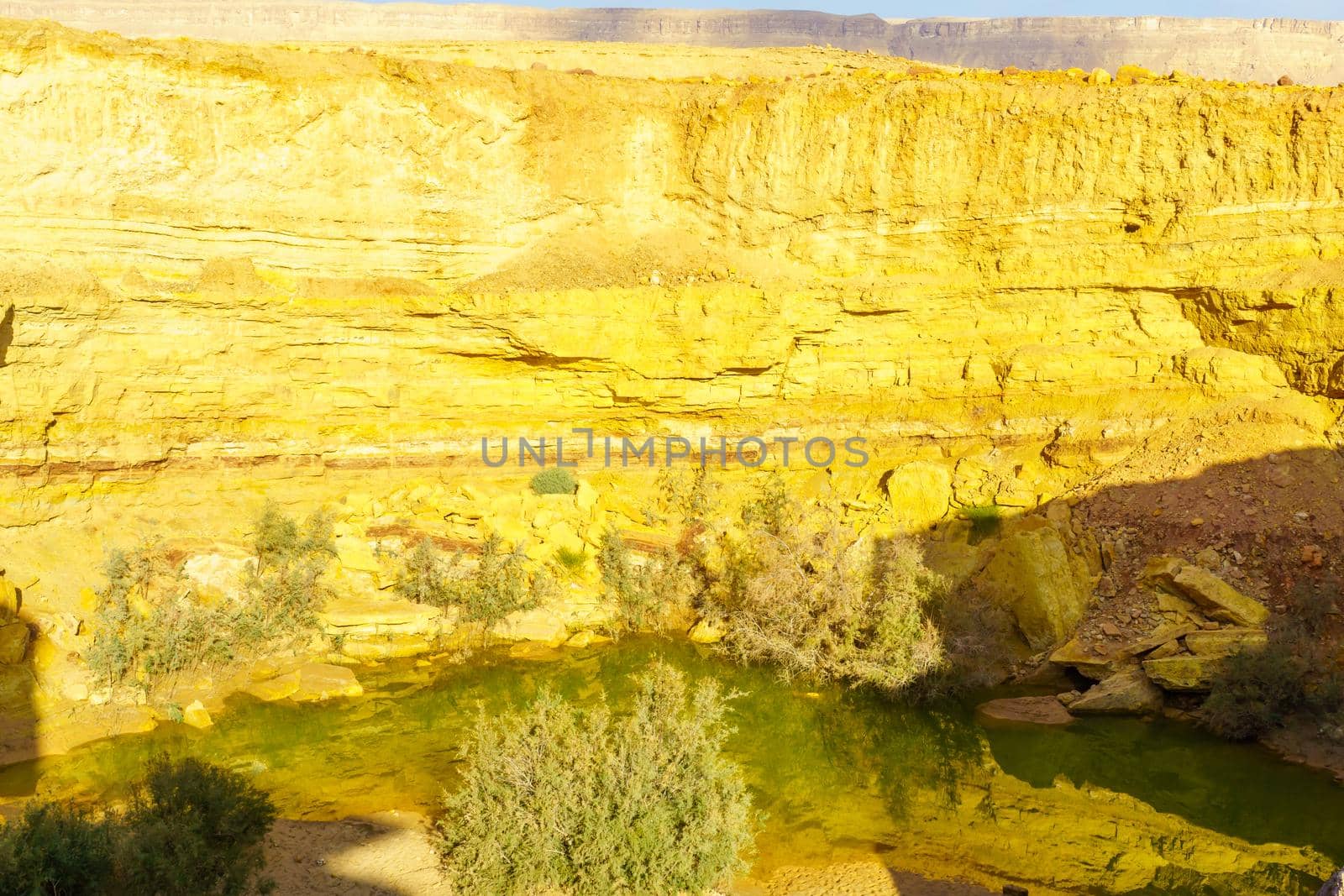 View of a water hole and layered rock formation, along the Ramon Colors Route, in Makhtesh Ramon (Ramon Crater), the Negev desert, southern Israel