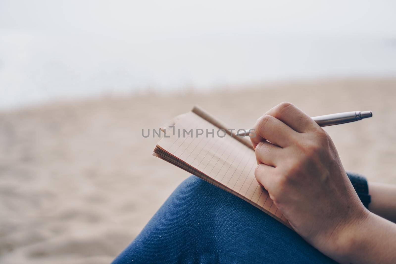 Woman hand writing down in small white memo notebook for take a note not to forget or to do list plan for future.