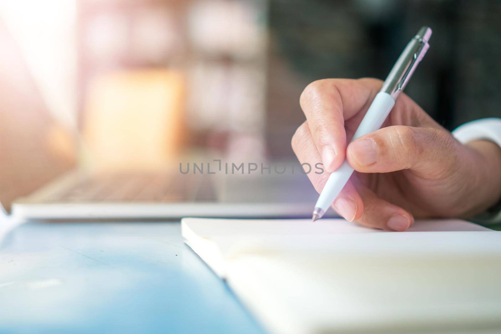 Woman hand writing down in small white memo notebook for take a note not to forget or to do list plan for future.