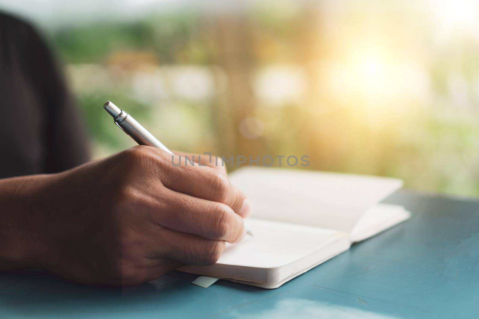 Woman hand writing down in small white memo notebook for take a note not to forget or to do list plan for future.