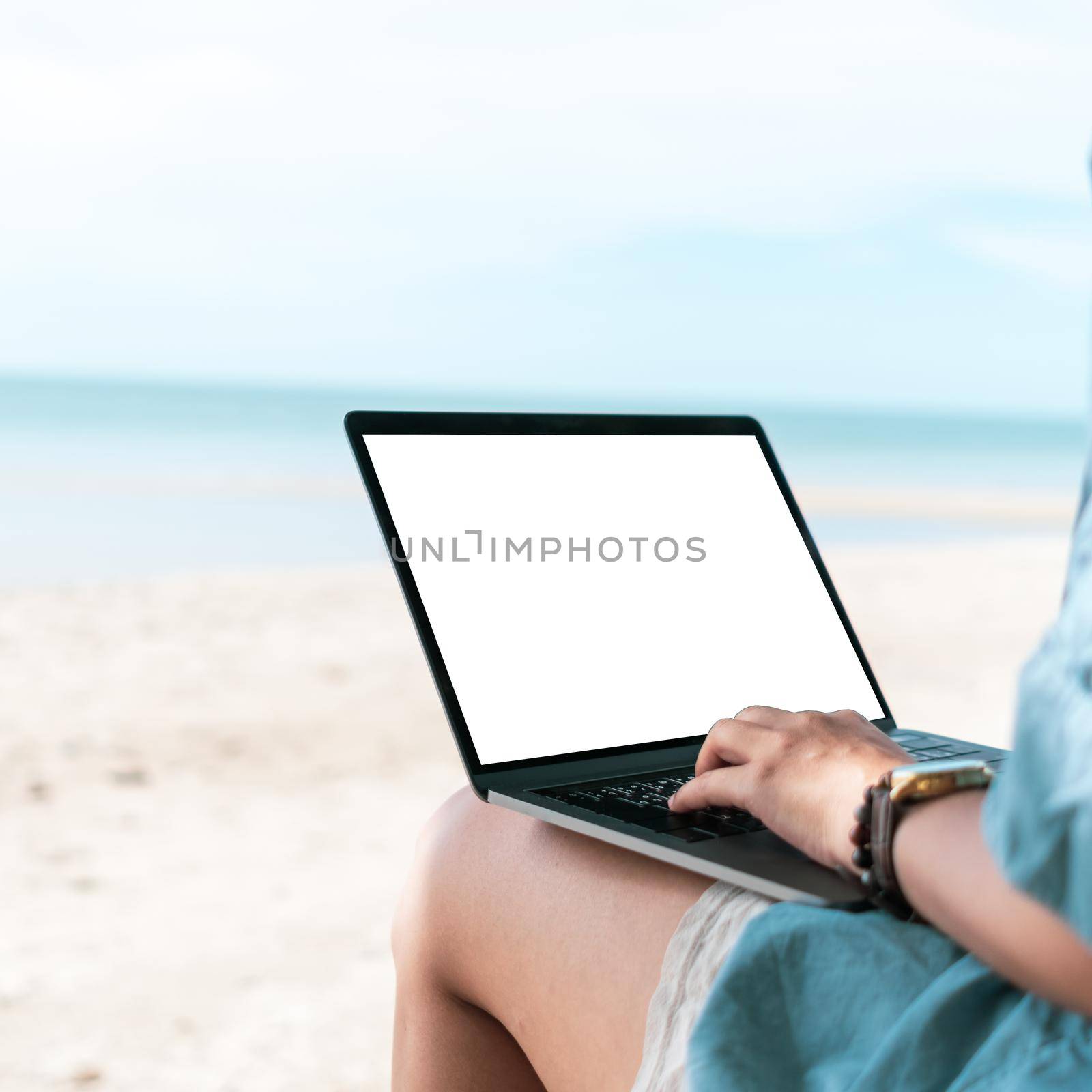 Woman using laptop with white screen background to work study on vacation days at beach background. Business, financial, trade stock maket and social network concept.