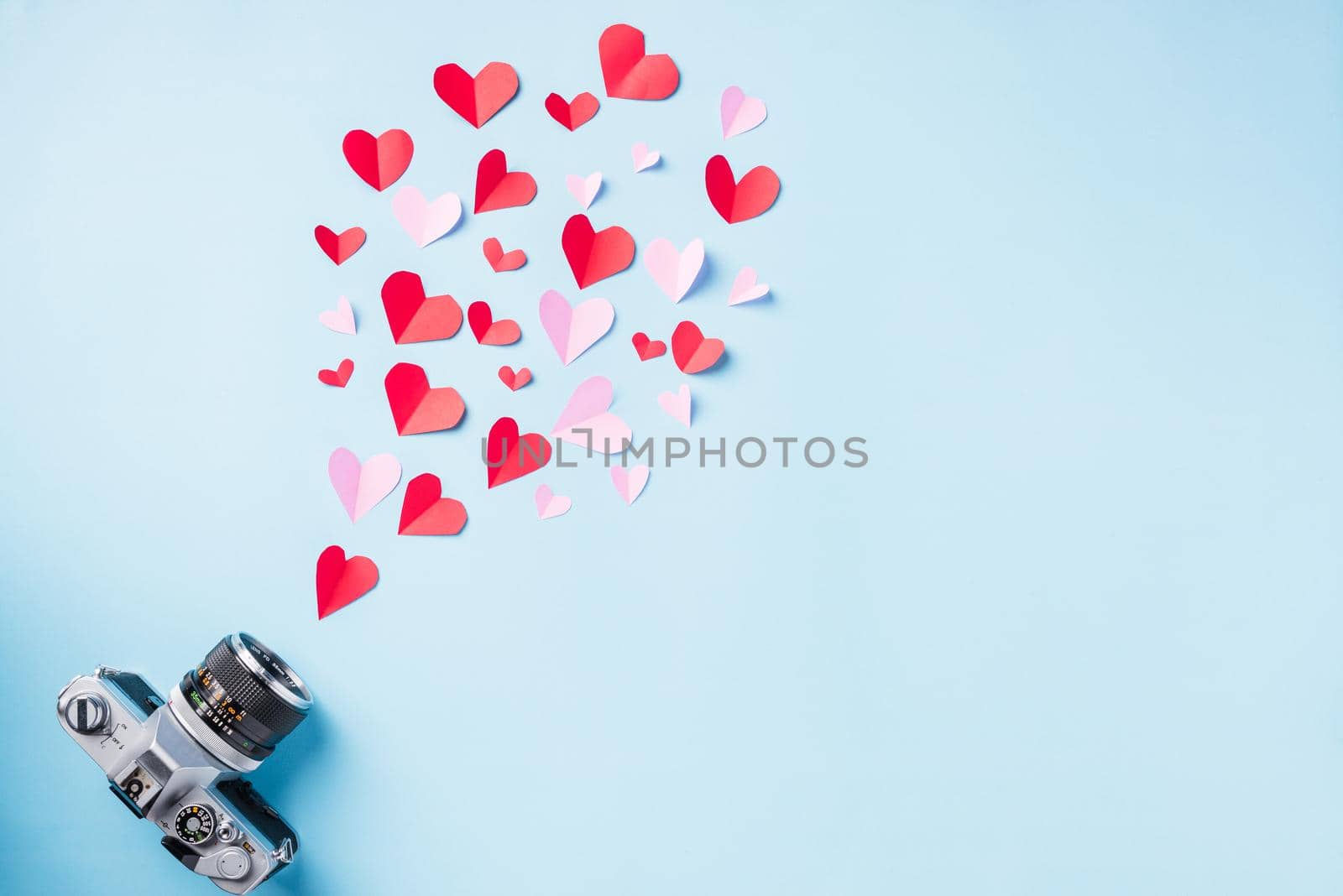 Valentines' day background. Vintage retro camera and paper flying elements hearts cut greeting gift card on blue background, Symbol of love. Happy Valentines Day and I love photography concept