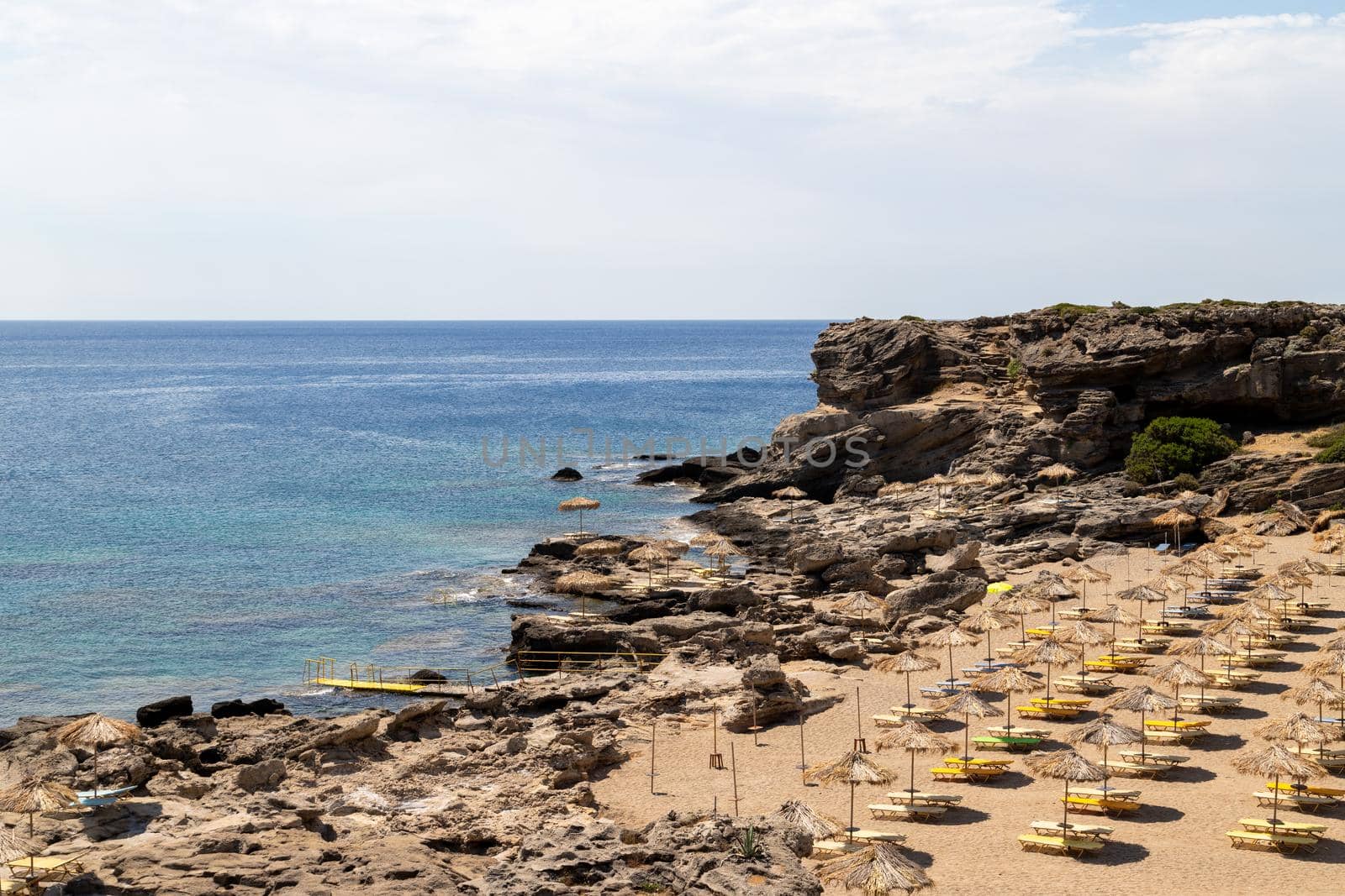 Scenic view at Kalithea beach on Geek island Rhodes with rocky coastline and sunshades on a sunny day in spring