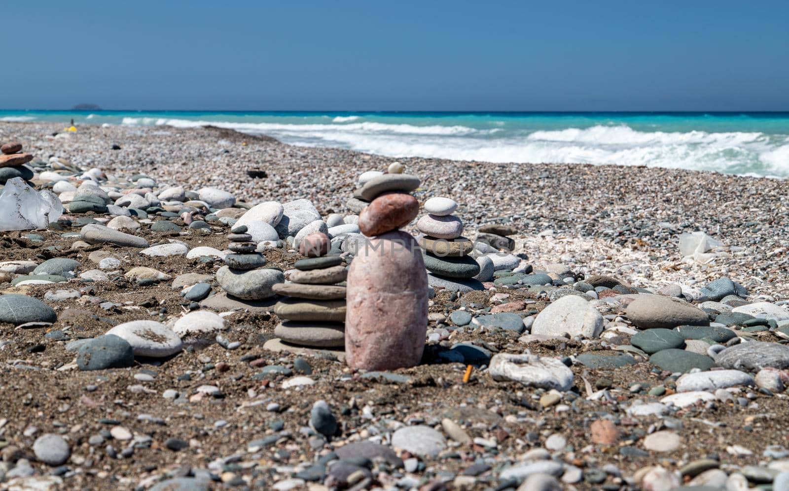 Gravel / pebble beach at the southwest coast of Rhodes island near Apolakkia with multi colored ocean water and small stone figures by reinerc