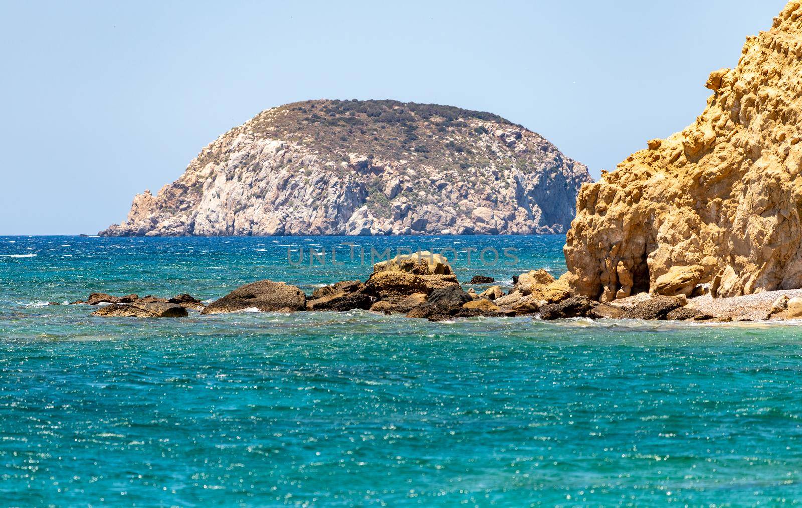 Gravel / pebble beach Akra Fourni nearby Monolithos  at Rhodes island with multi colored ocean water, waves and rocks 