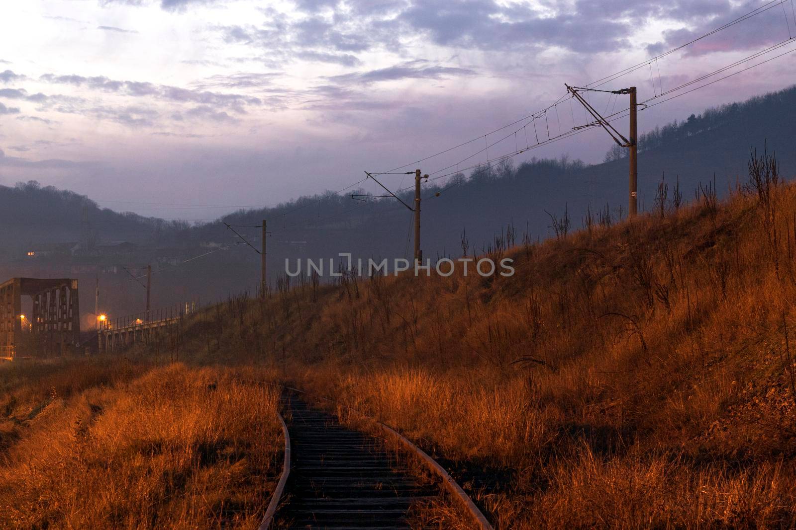 Train line approaching a bridge at sunset