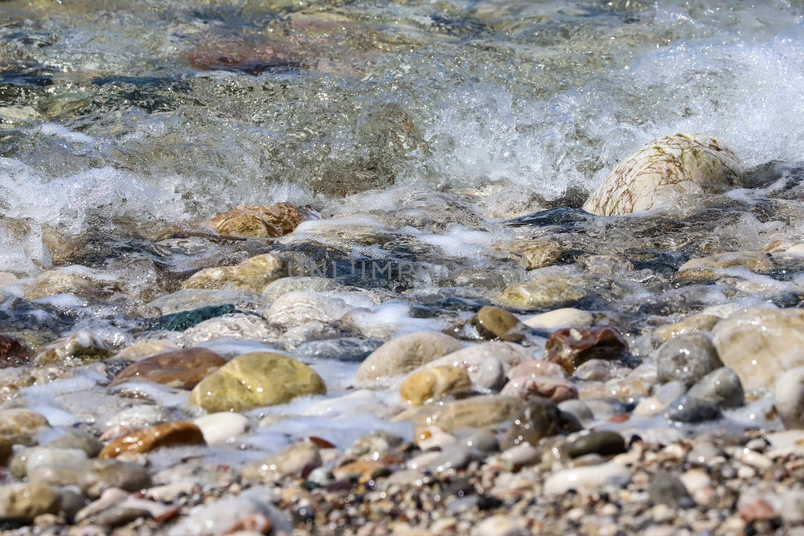 Close-up of ocean water flowing over pebble stones on a beach at Rhodes island, Greece