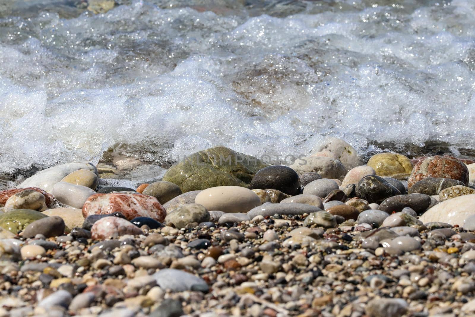 Close-up of ocean water flowing over pebble stones on a beach at Rhodes island, Greece