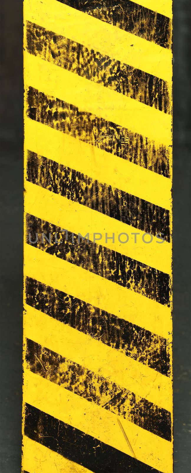 Old yellow weathered painted background with grunge black hazard sign stripes over dark