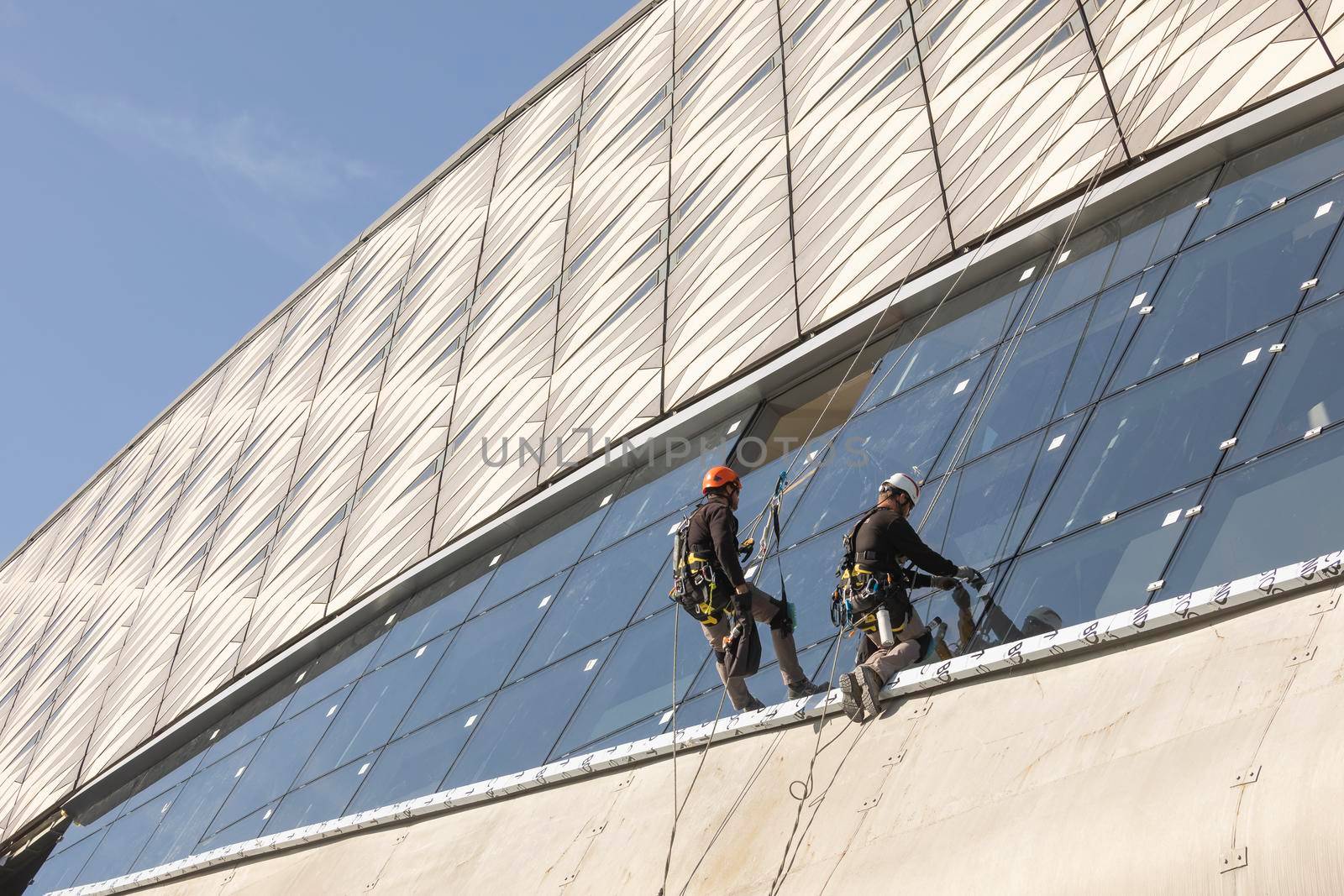 Zaragoza, Spain - Sep. 30, 2020: Specialist technical workers carry out maintenance and rehabilitation work, wearing safety harnesses, on the facade of the Zaragoza bridge pavilion.