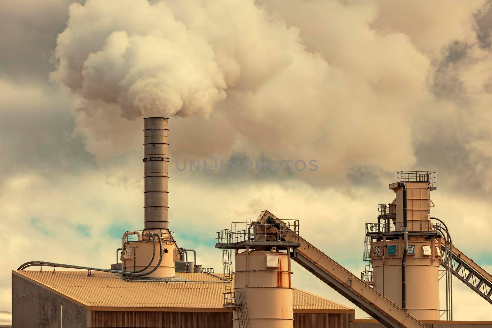A large manufacturing facility with steam coming from chimney st by WittkePhotos