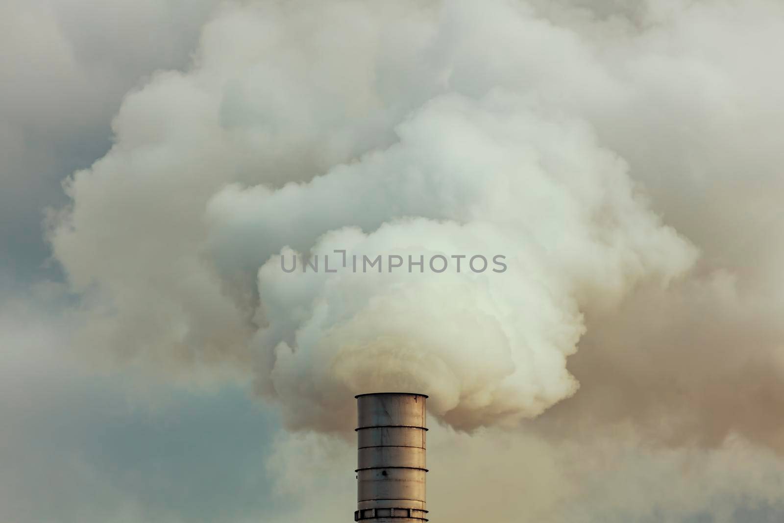 A large manufacturing facility with steam coming from chimney st by WittkePhotos