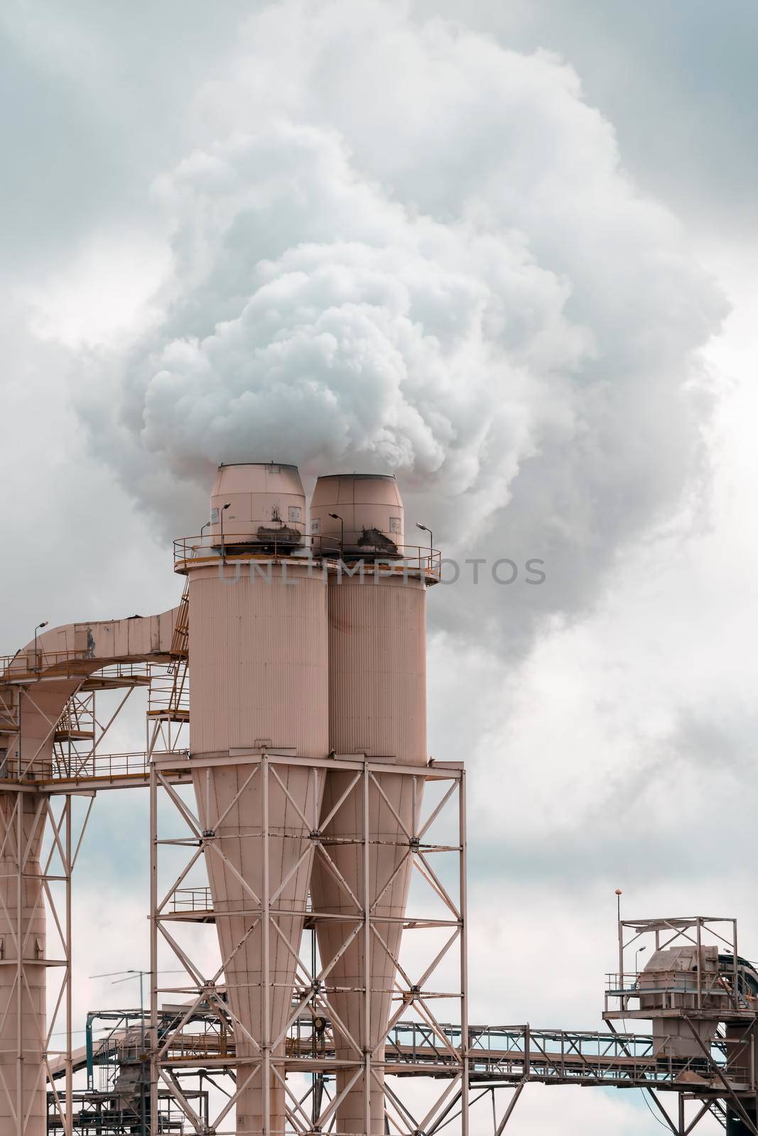 A large manufacturing facility with steam coming from chimney st by WittkePhotos