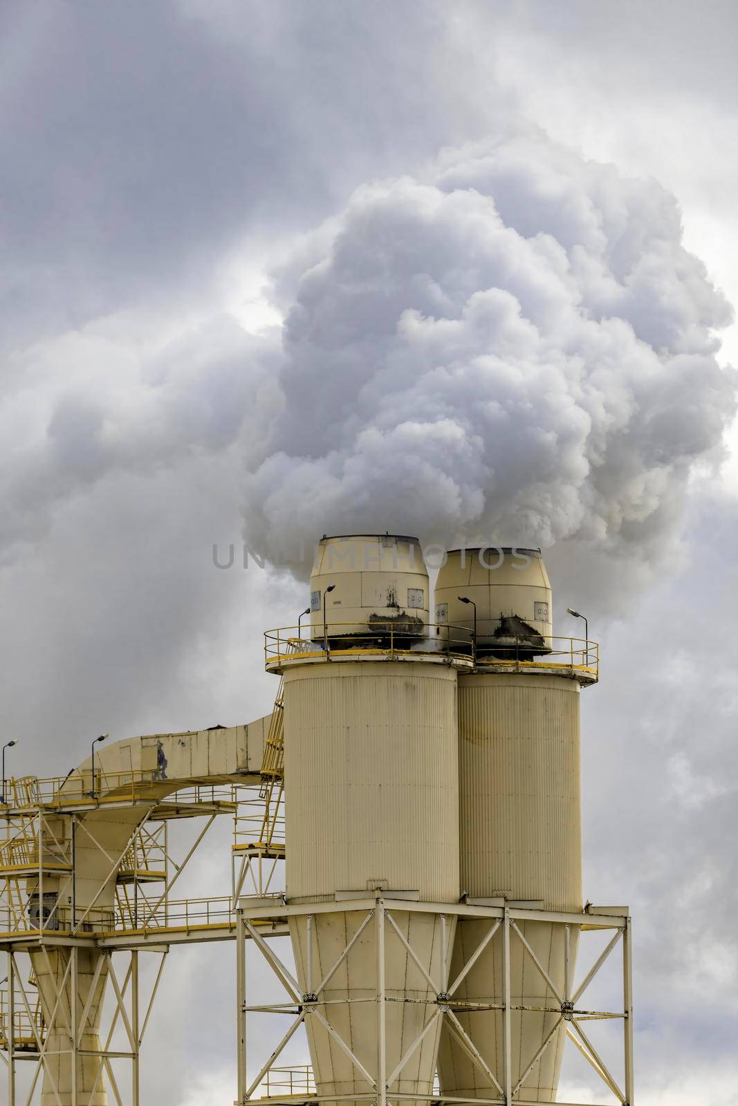 A large manufacturing facility in a regional township with steam coming from the chimney stacks during processing