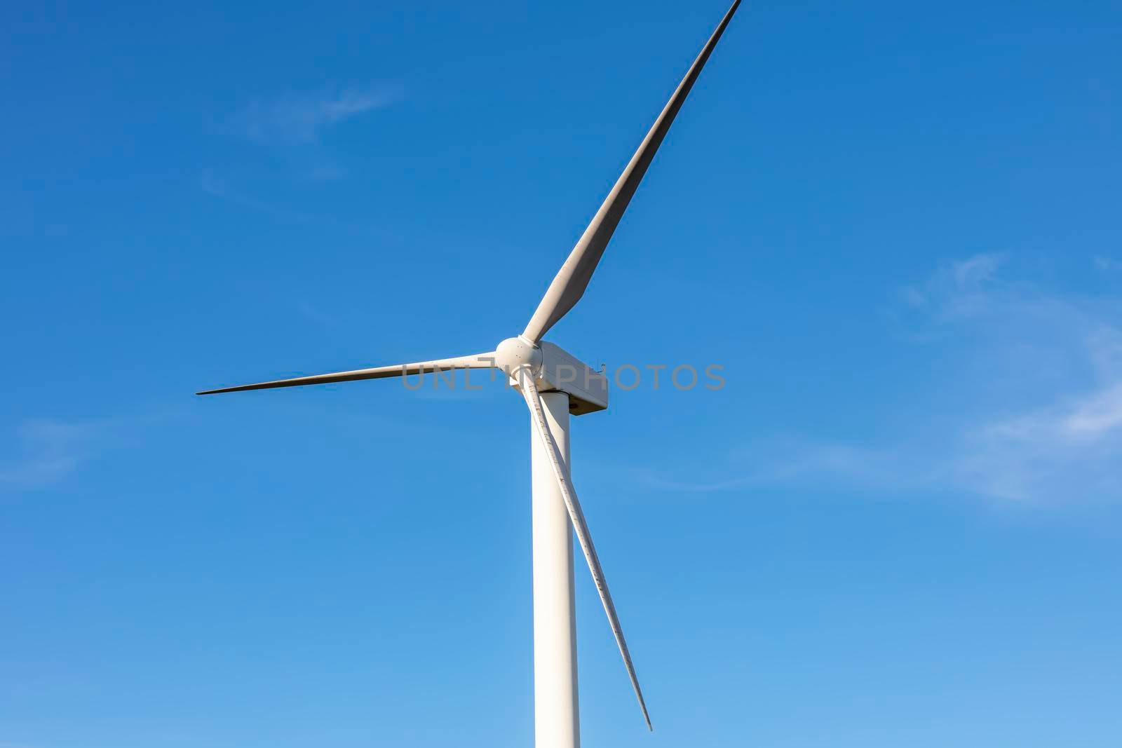 A large three blade industrial wind turbine generating electricity in a wind farm