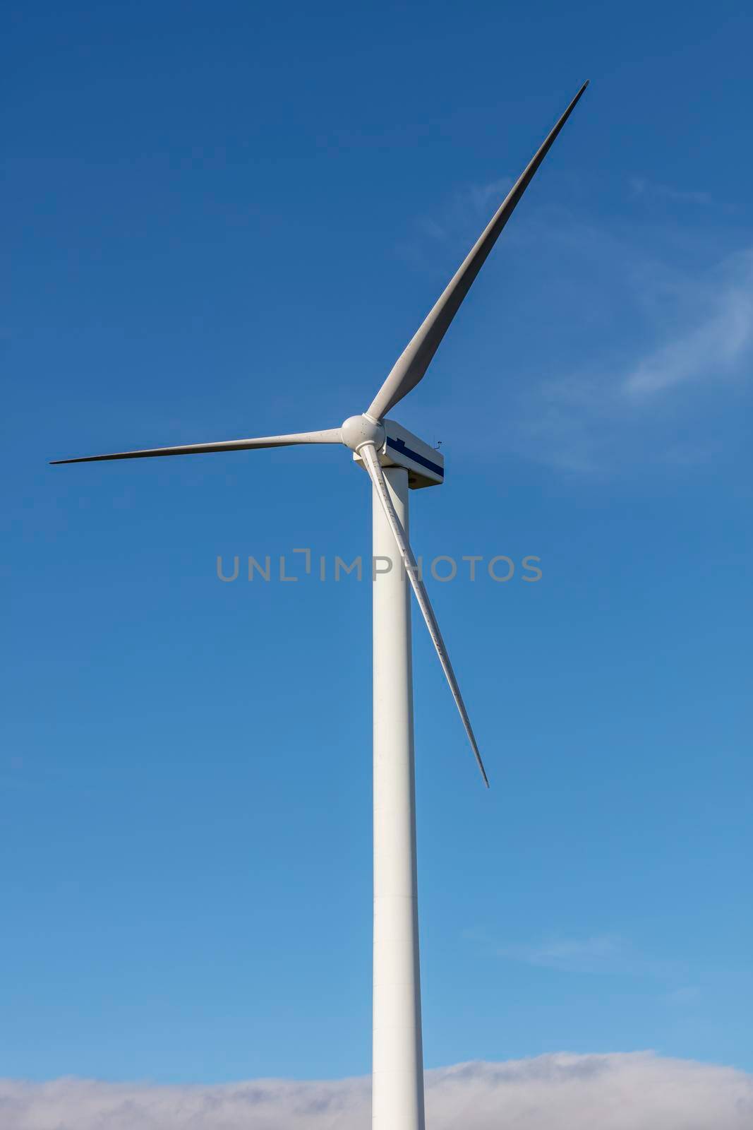 A large three blade industrial wind turbine generating electricity in a wind farm