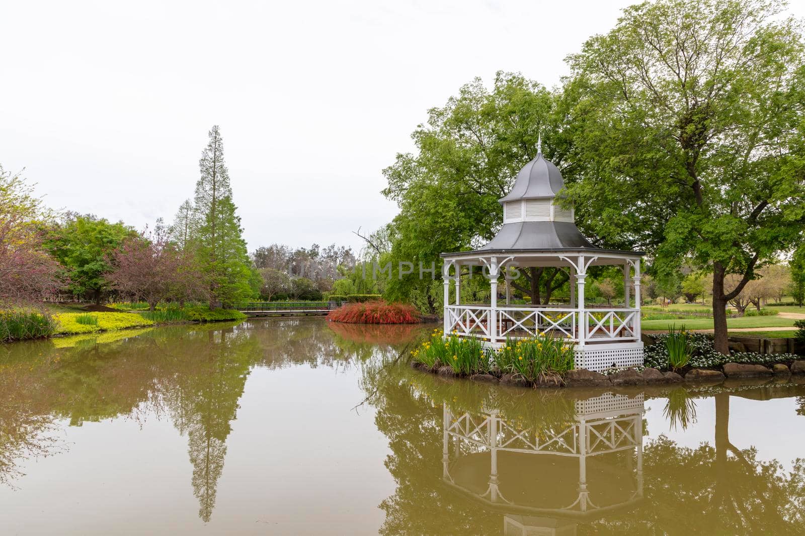 A white pagoda surrounded by trees on a garden pond by WittkePhotos