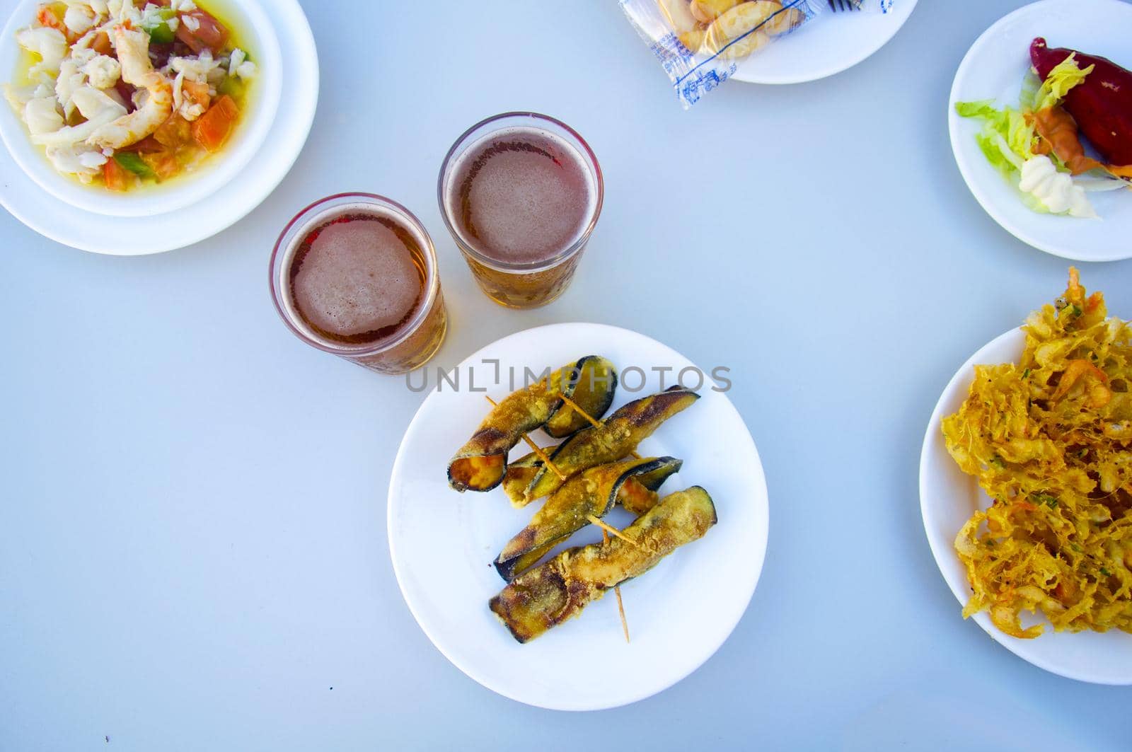 Fried eggplants rolled up with shrimps inside, two beers and other plates, above