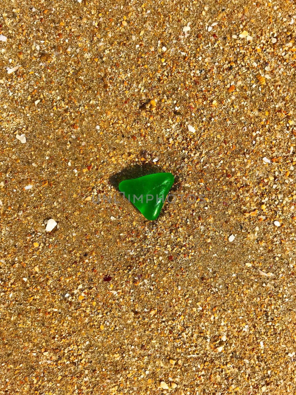Green triangle glass on the yellow sand, summer, morning