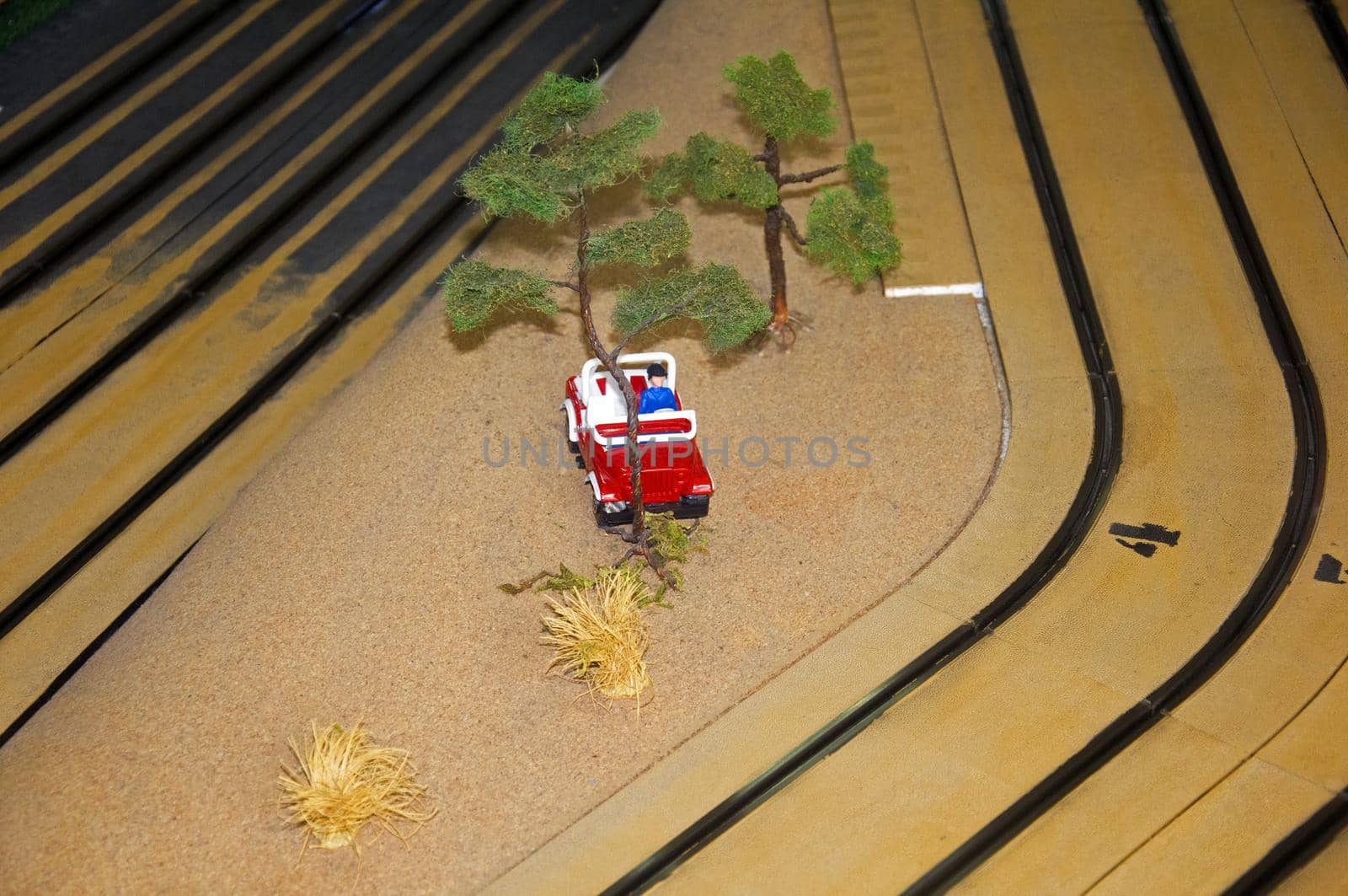 Small toy house, red car, trees and lantern in toy track, macro