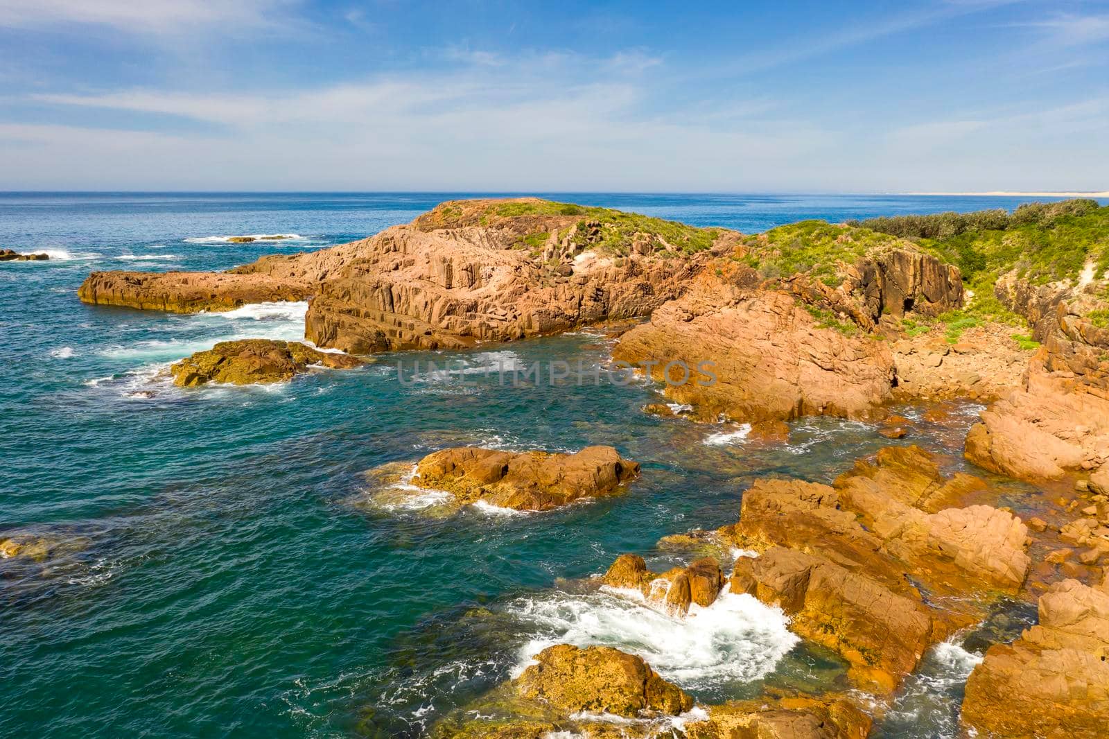 Aerial view of the brown Rocks and blue water of the Tasman Sea at Birubi Point near Port Stephens in regional New South Wales in Australia