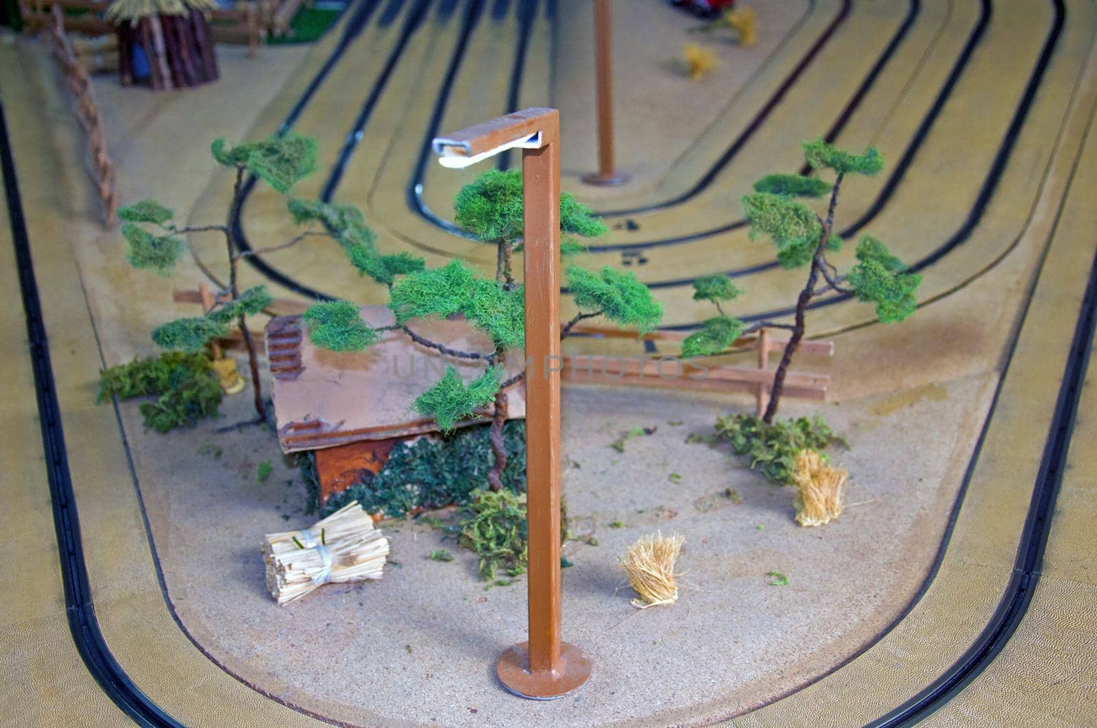 Small toy house, trees and lantern in toy track, front up view