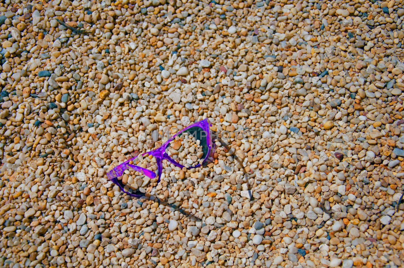 Violet sunglasses on the multi colored gravel stones, summer, Spain