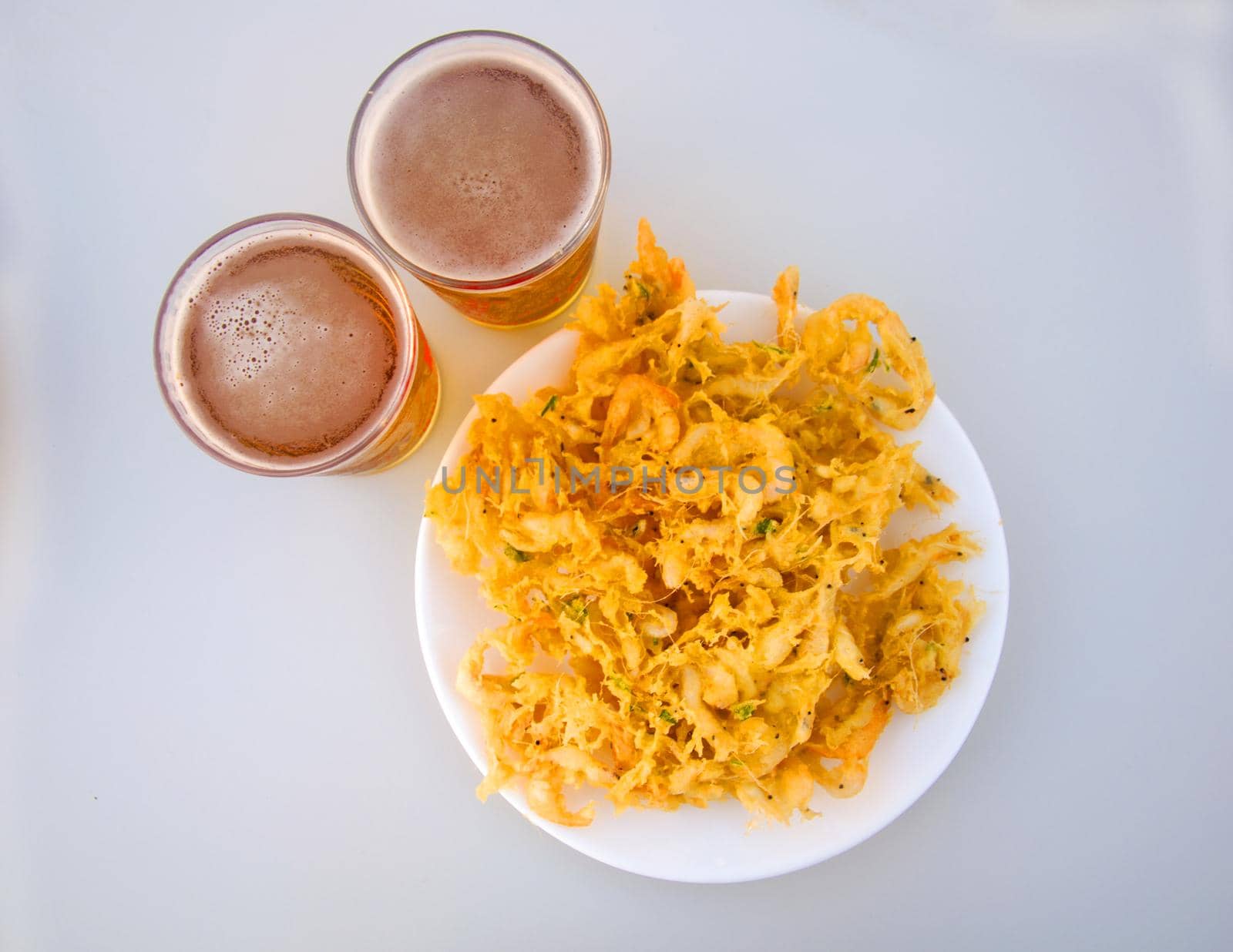 Fried yellow fritters with small shrimps and two beers, isolated