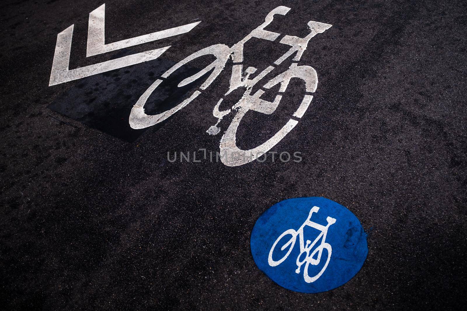 Cycle path markings on a black asphalt background viewed from high angle. Two different bike symbol and direction arrow. Road markings used in some areas in the city of Barcelona (Spain).