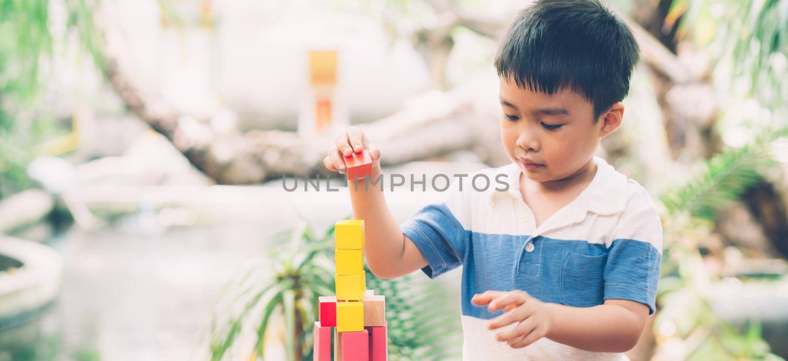 Asian young boy playing wooden block toy on table for creative and development, happy child learn skill for activity puzzle and creativity for game on desk at home, education concept, banner website. by nnudoo