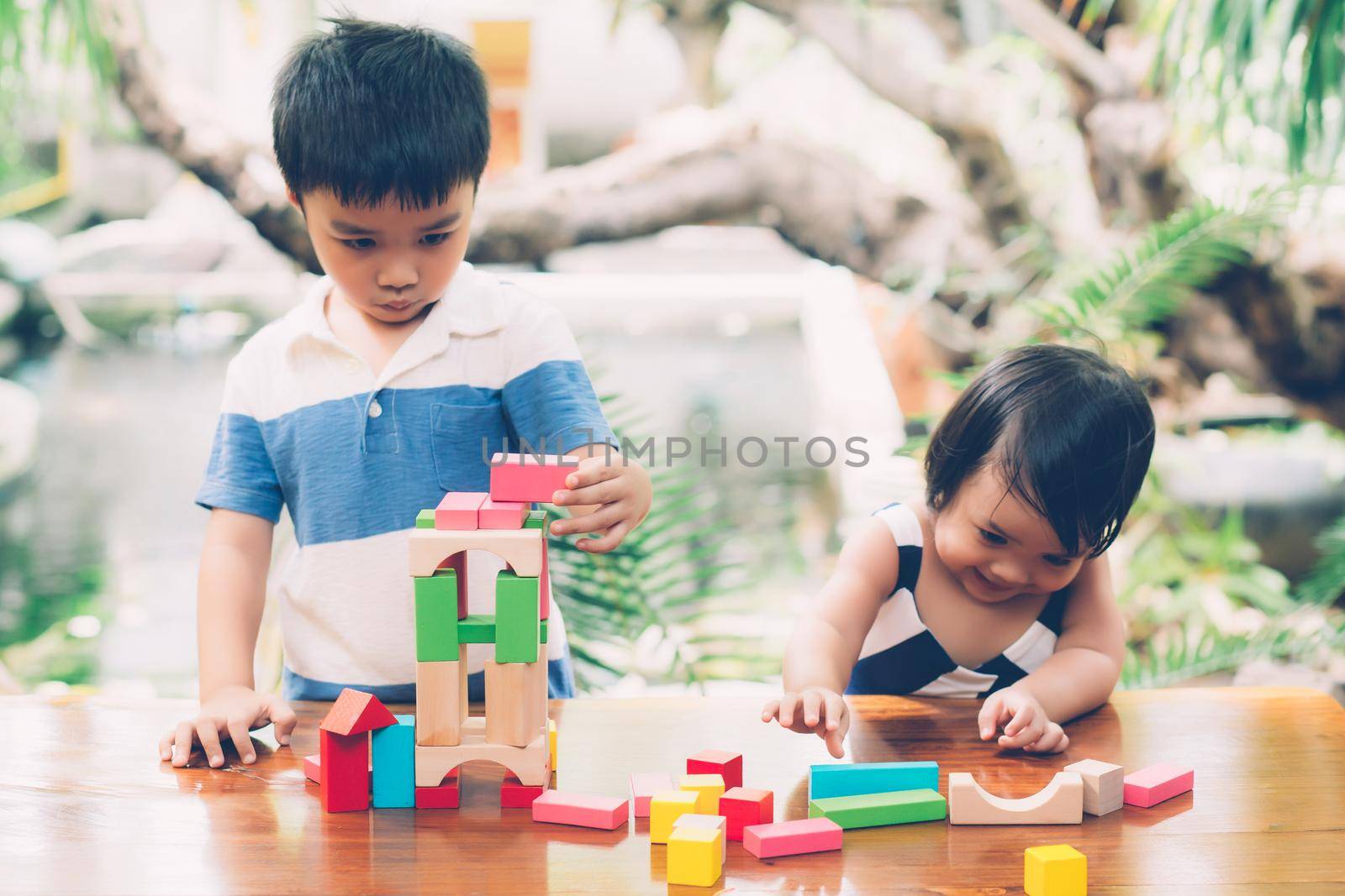 Asian boy and gril playing wooden block toy on table for creative and development with enjoy, happy child learn skill for activity puzzle and creativity for game on desk at home, education concept. by nnudoo