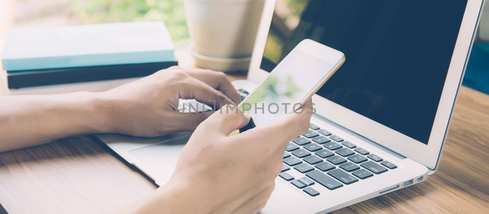 Hand of business man working from home using laptop computer to internet online on desk, new normal, social distancing, freelance work and look phone, communication concept, banner website.