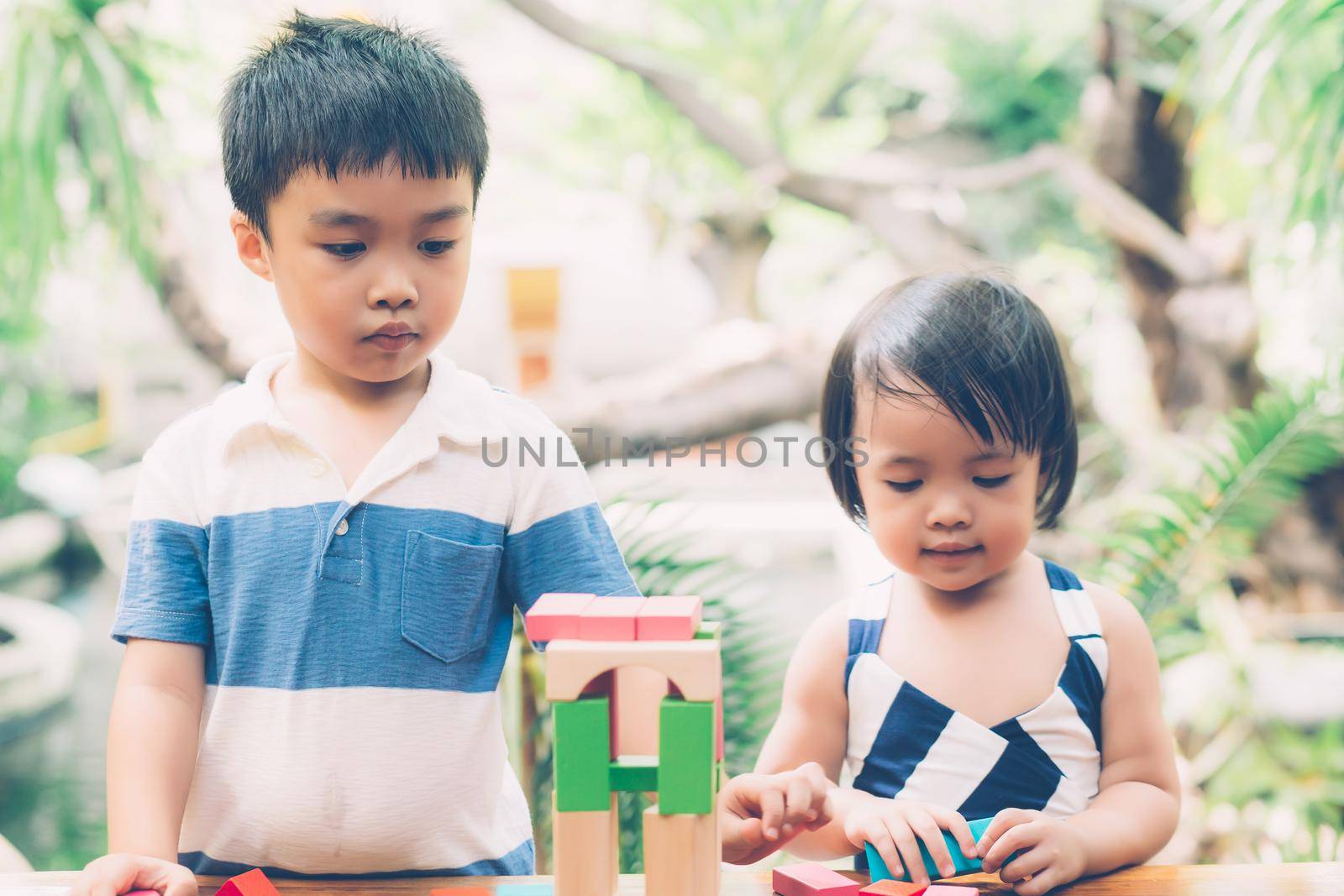 Asian boy and gril playing wooden block toy on table for creative and development with enjoy, happy child learn skill for activity puzzle and creativity for game on desk at home, education concept. by nnudoo