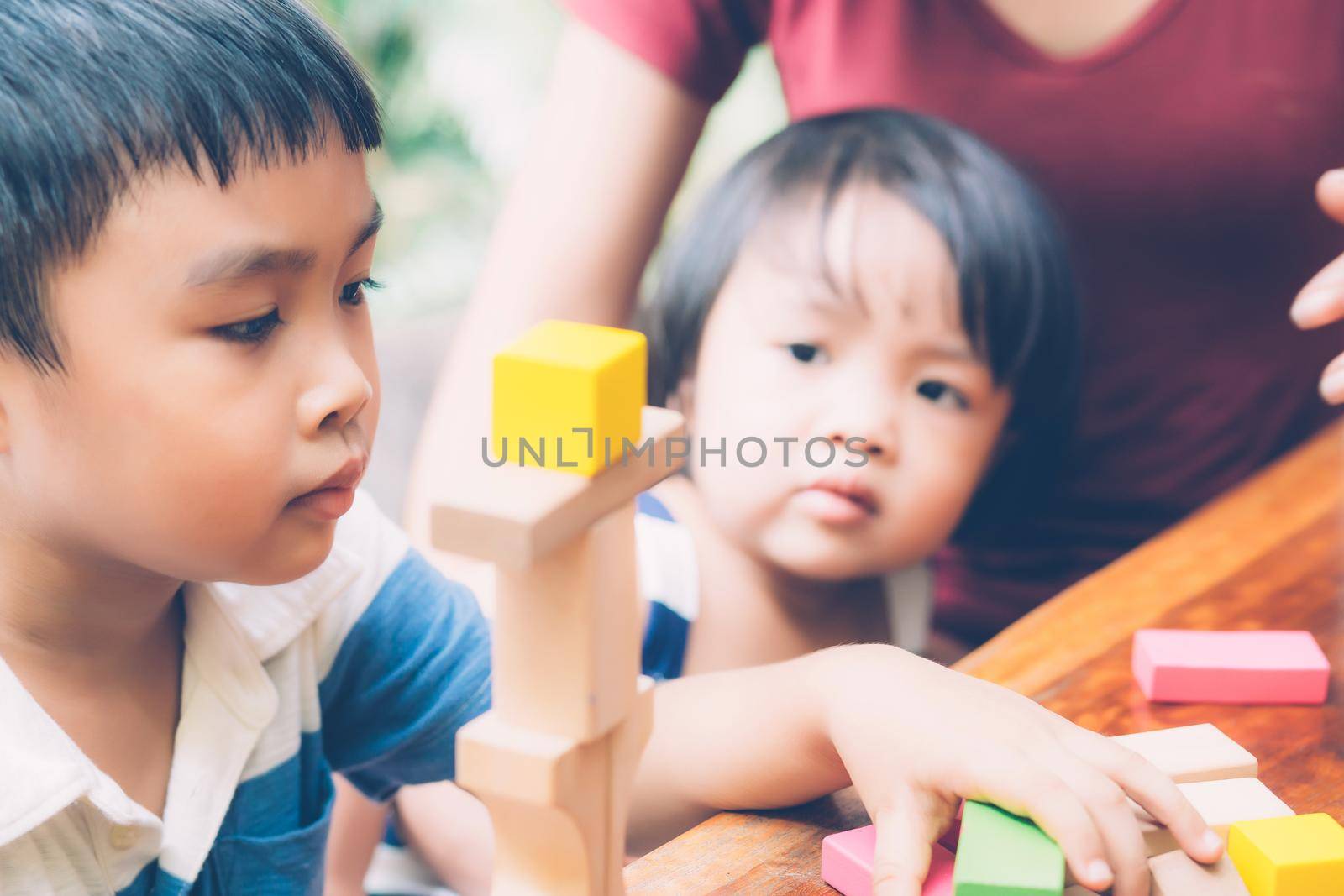 Family with asian mother and children playing toy block at home, mom and son and daughter doing activity and hobby about learning and development, creative and imagination, education concept. by nnudoo