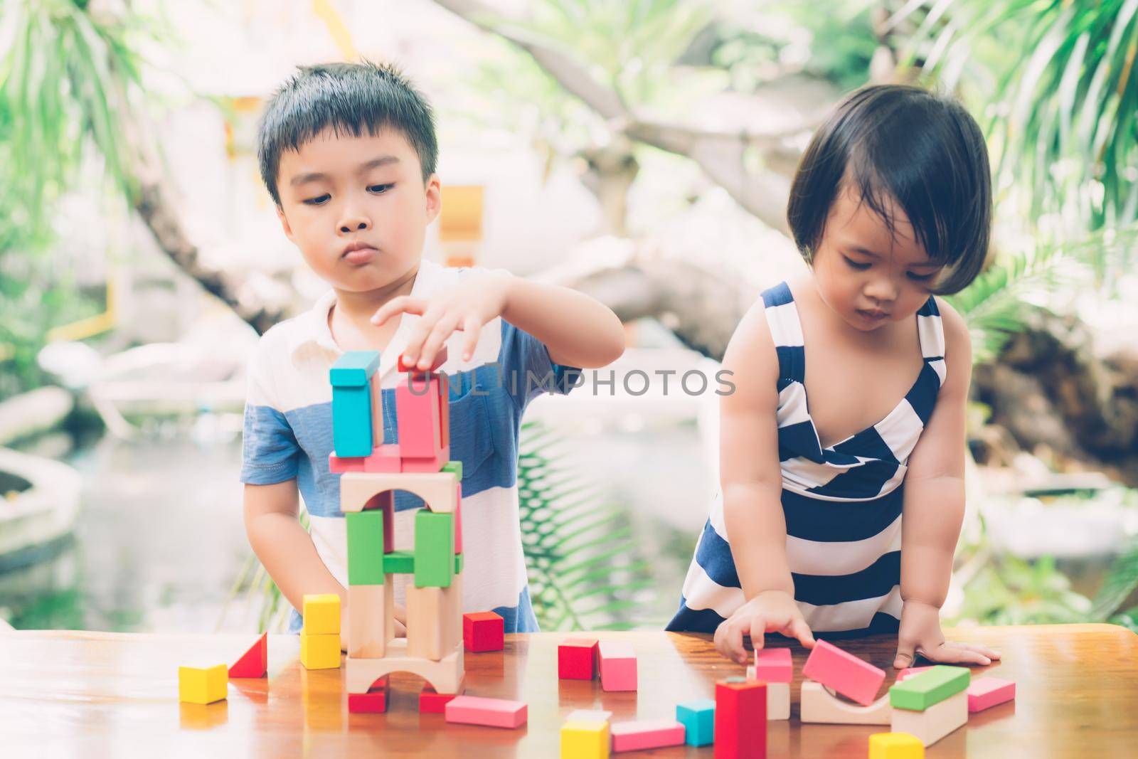 Asian boy and gril playing wooden block toy on table for creative and development with enjoy, happy child learn skill for activity puzzle and creativity for game on desk at home, education concept.