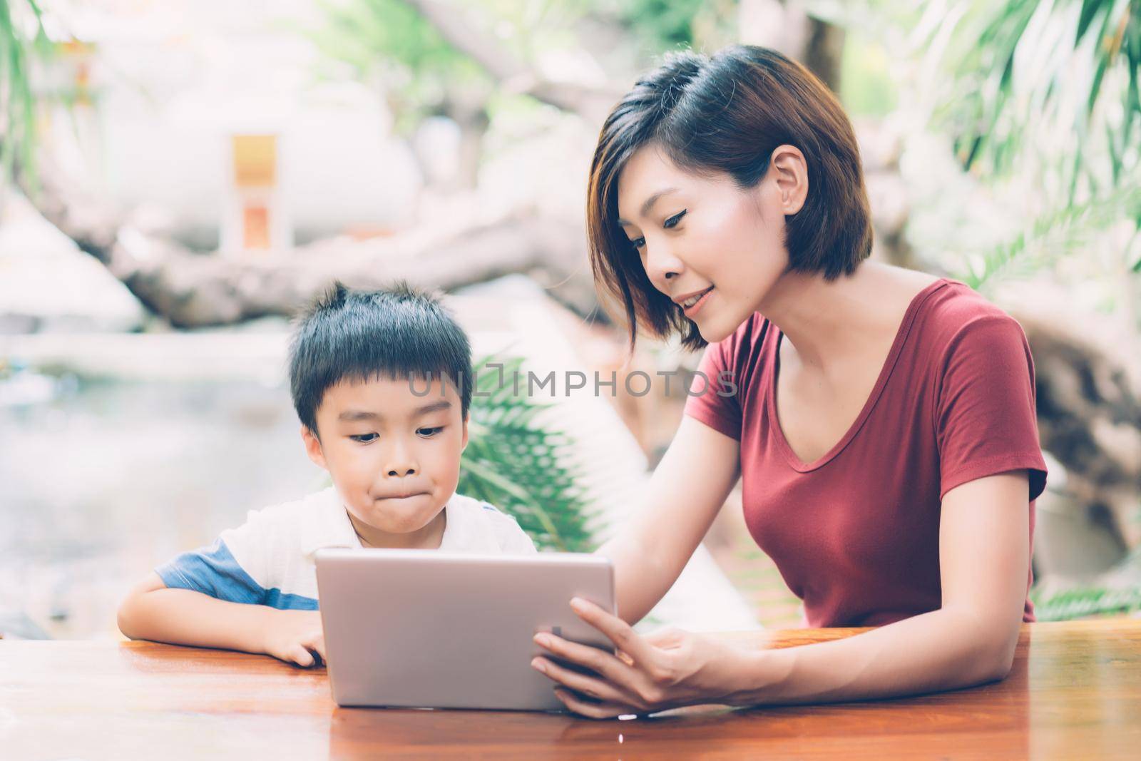 Son using digital tablet computer for study and learn to internet online with mother together, education from home, family recreation, mom teach boy with technology media, lifestyle concept. by nnudoo